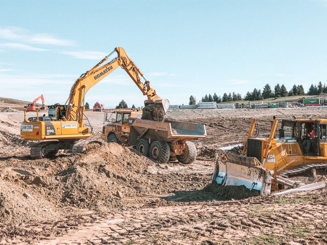 Excavator loading a dump truck with a dozer alongside