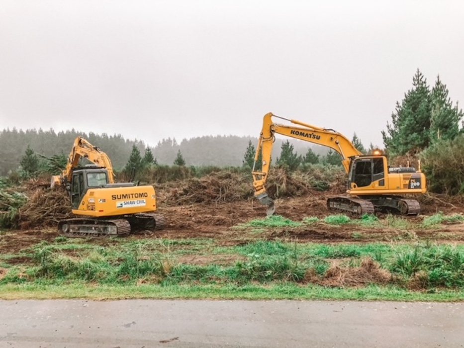 Two Shaw Civil excavators clearing land beside a road